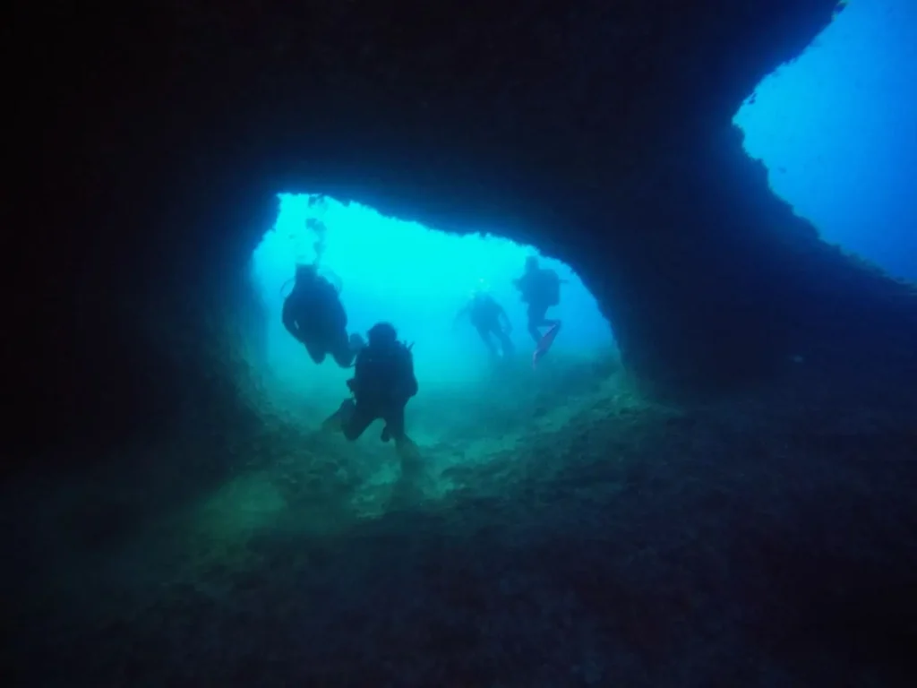 Buceador entrando en la cueva de la luz en columnas de Hércules Ibiza