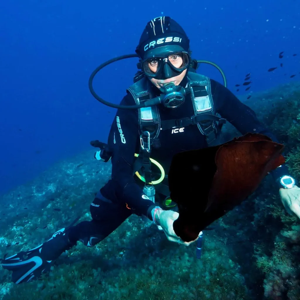 Buceador explorando La Bota en Ibiza junto a pez grande en fondo rocoso